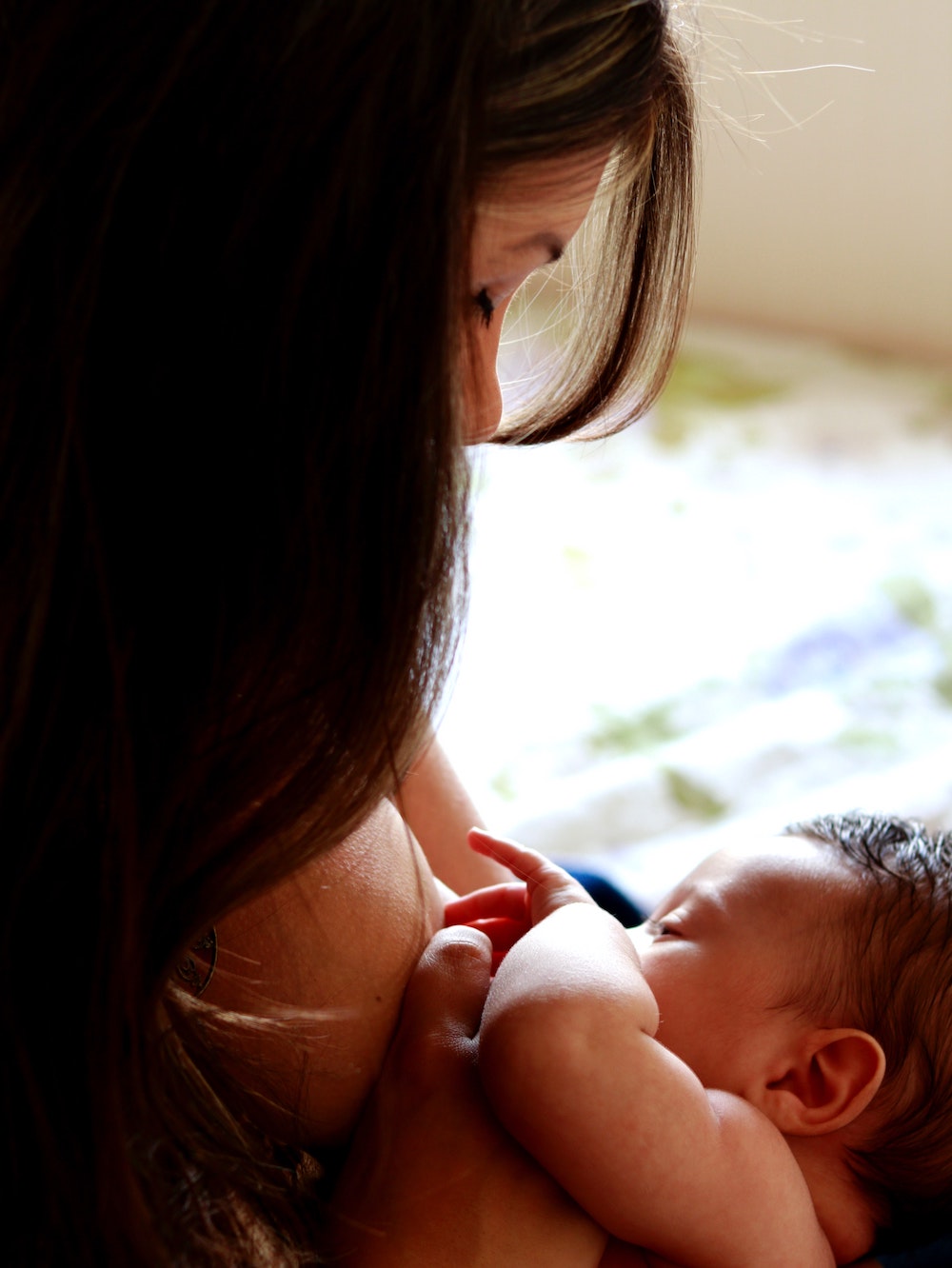 newborn baby nursing skin to skin with dark haired mother
